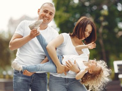 Happy family enjoying playful moments outside on a sunny day.